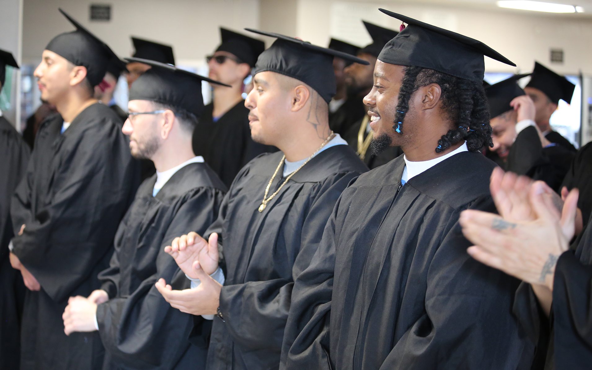 Incarcerated students applaud others as they receive their GEDs or college degrees.