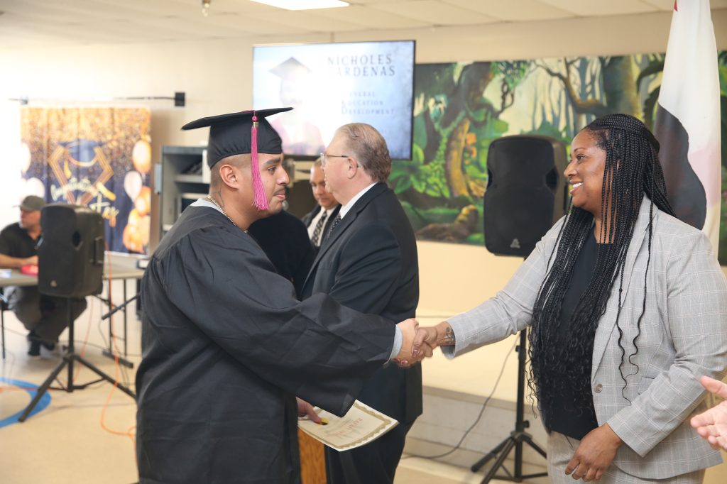 Acting Warden A. Williams shakes hands with a graduate. 