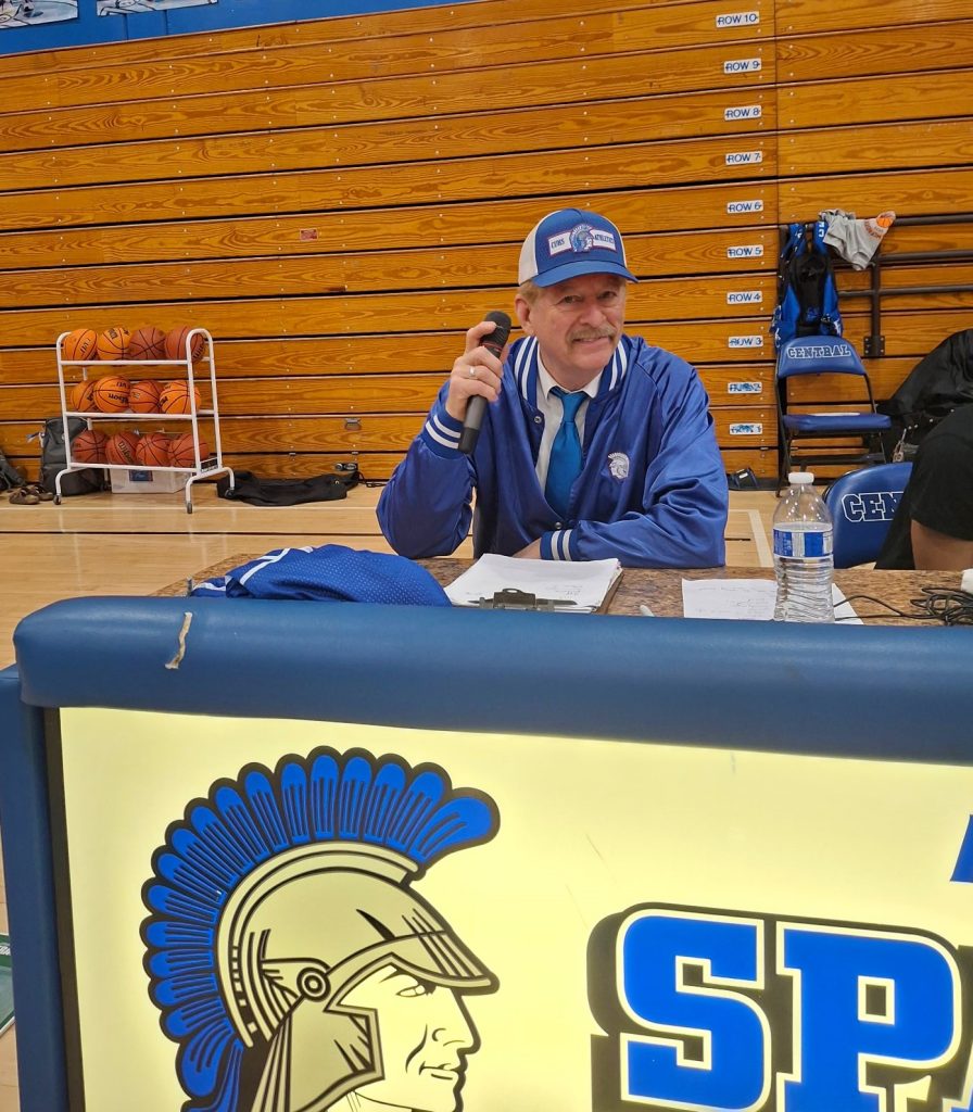 Brian Barrett holding a microphone at an atheltic event