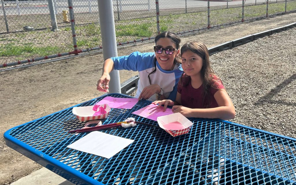 Incarcerated woman and female child work on a Valentine's Day painting craft together