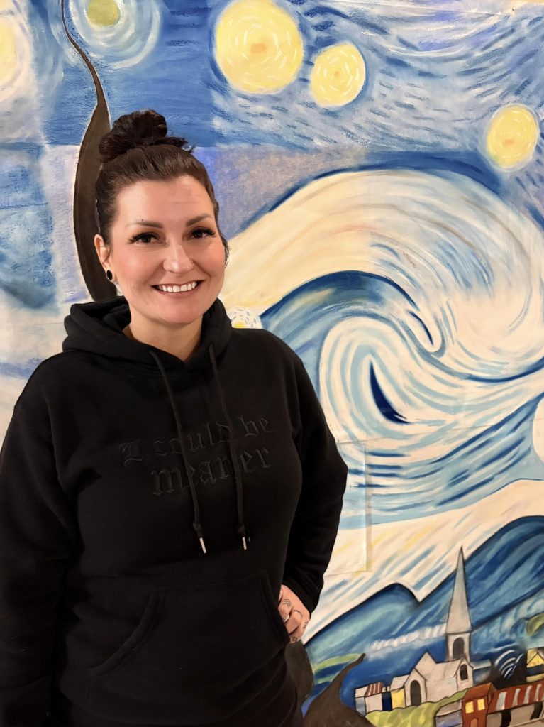 Recreation therapist Megan Waters stands in front of SAC mural