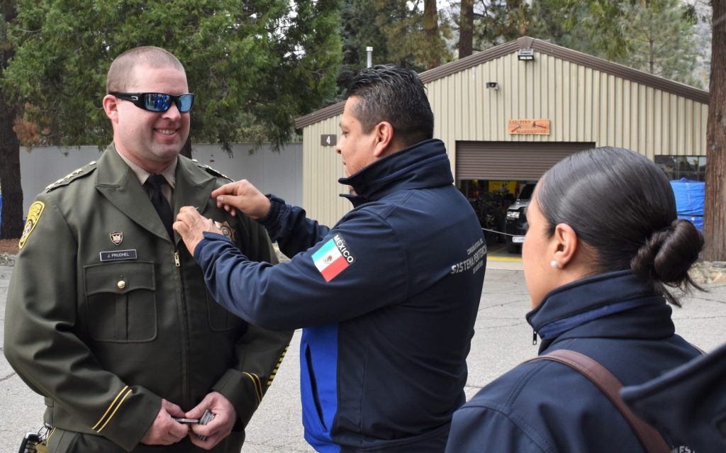 A Mexico prison official presents a thank-you pin to the Sierra Conservation Center warden.