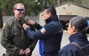 A Mexico prison official presents a thank-you pin to the Sierra Conservation Center warden.