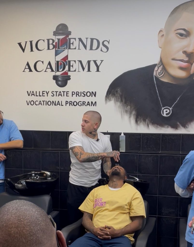 A barber, Vic Blends, demonstrates techniques at the barbershop. 