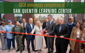 Governor Gavin Newsom stands in a small group as he cuts the ribbon for the San Quentin Learning Center completion event