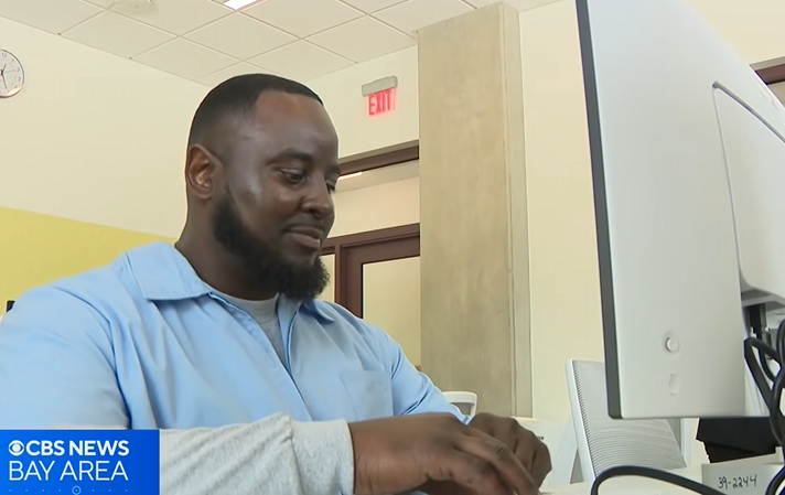 Incarcerated individual typing at a computer