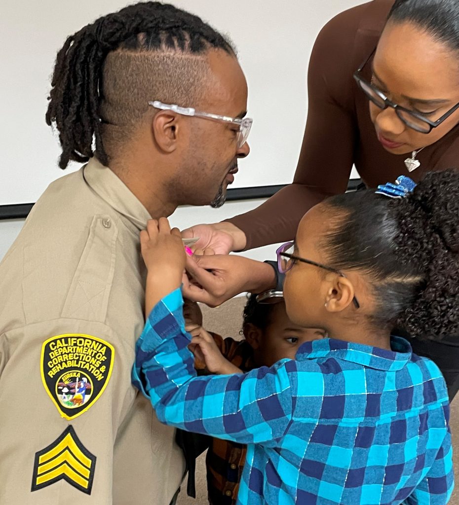 Family pins new rank insignia on a recently promoted sergeant at CHCF in Stockton, Feb. 20, 2026.