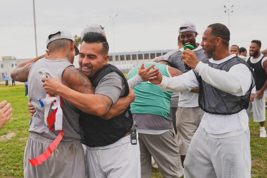 Post-game hugs and handshakes on the field after a game of flag football at CIM in Chino.