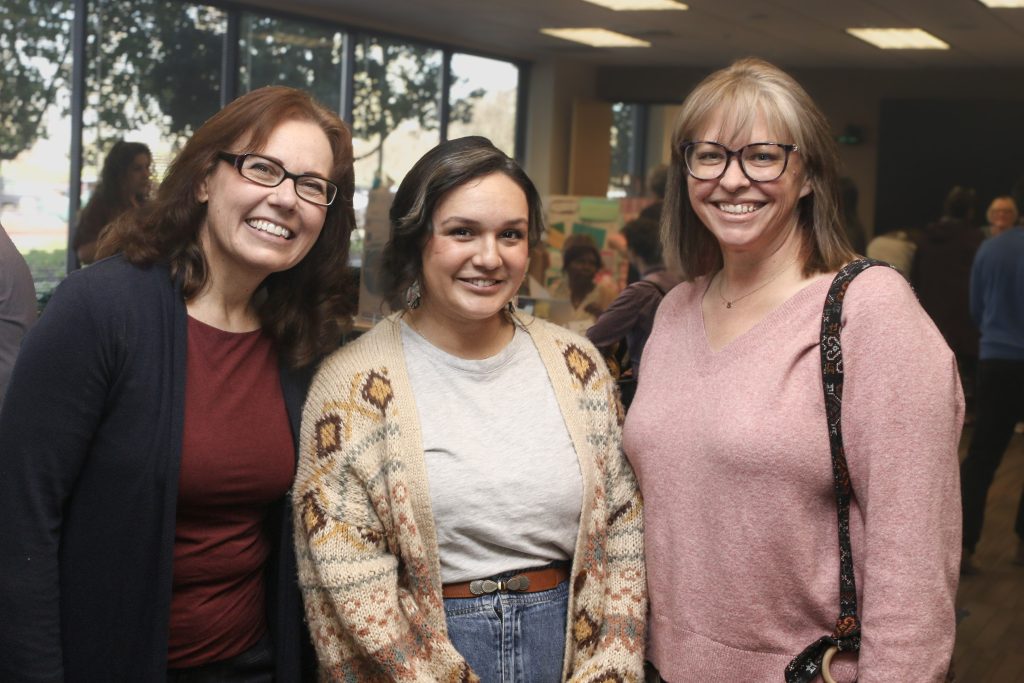 Three smiling CDCR employees standing together at headquarters event