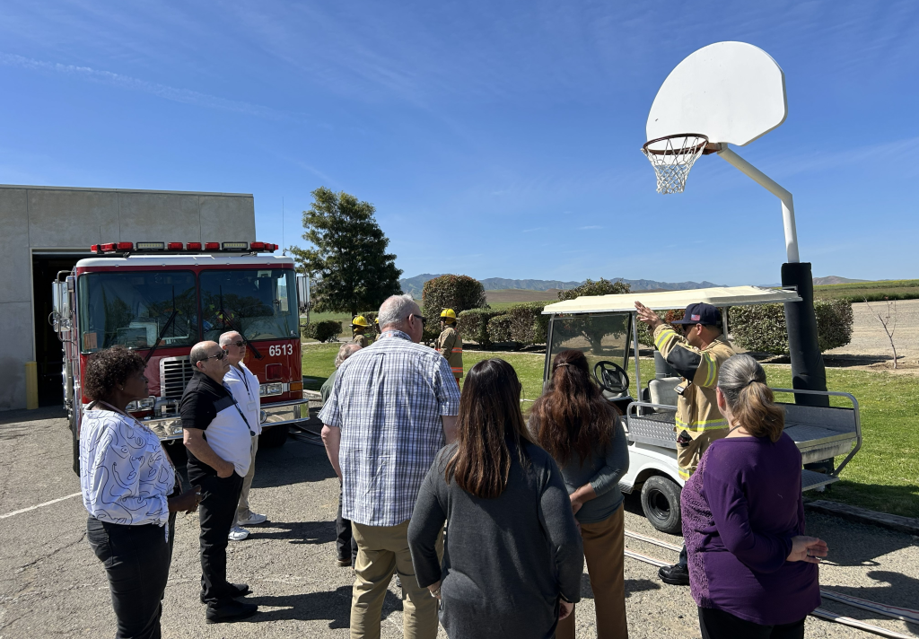 Group of people stand and listen to firefighter speaker