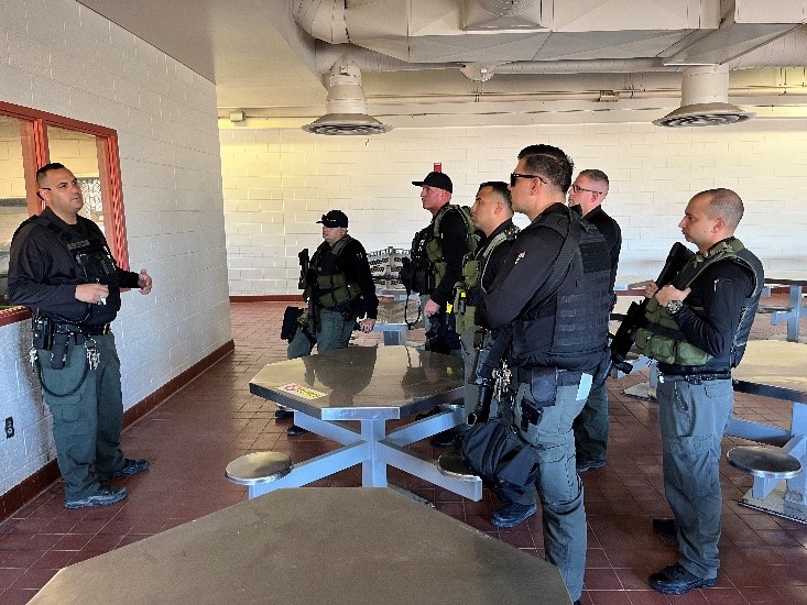 LAC Institutional Gang Investigations unit staff stand together listening to speaker