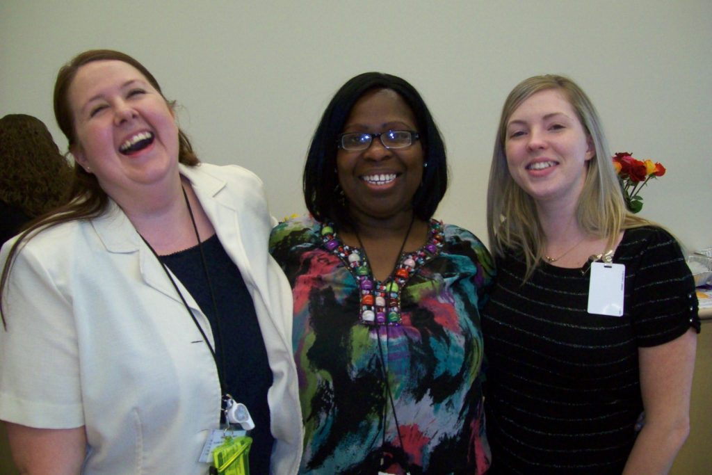 Three female CDCR staff members stand together, woman on left laughing