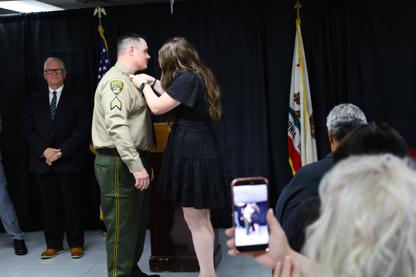 A family member pins the rank insignia on her loved one who promoted to sergeant at MCSP.