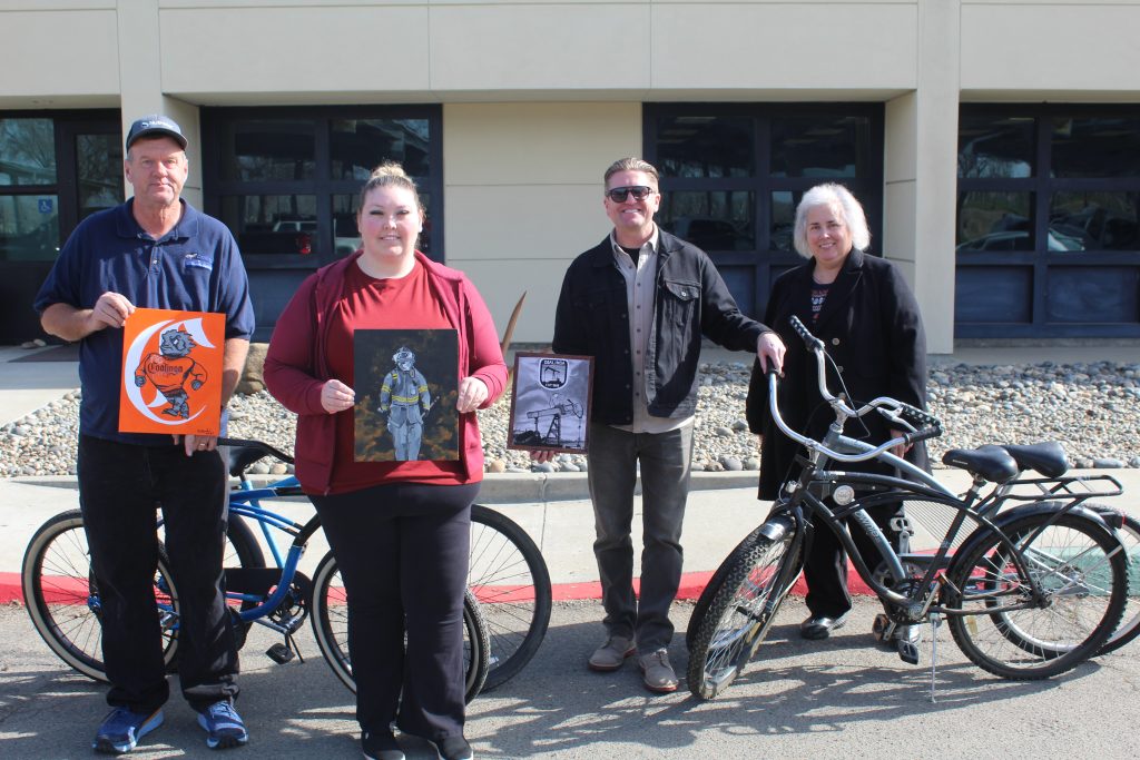 Four PVSP staff stand with artwork and bikes