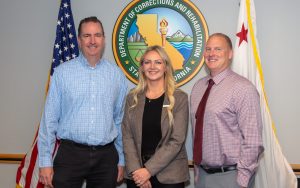 CDCR Secretary Jeff Macomber congratulates Governor's Innovation Fellows graduates Associate Warden Samantha Kissane and Associate Warden Chris Siino.