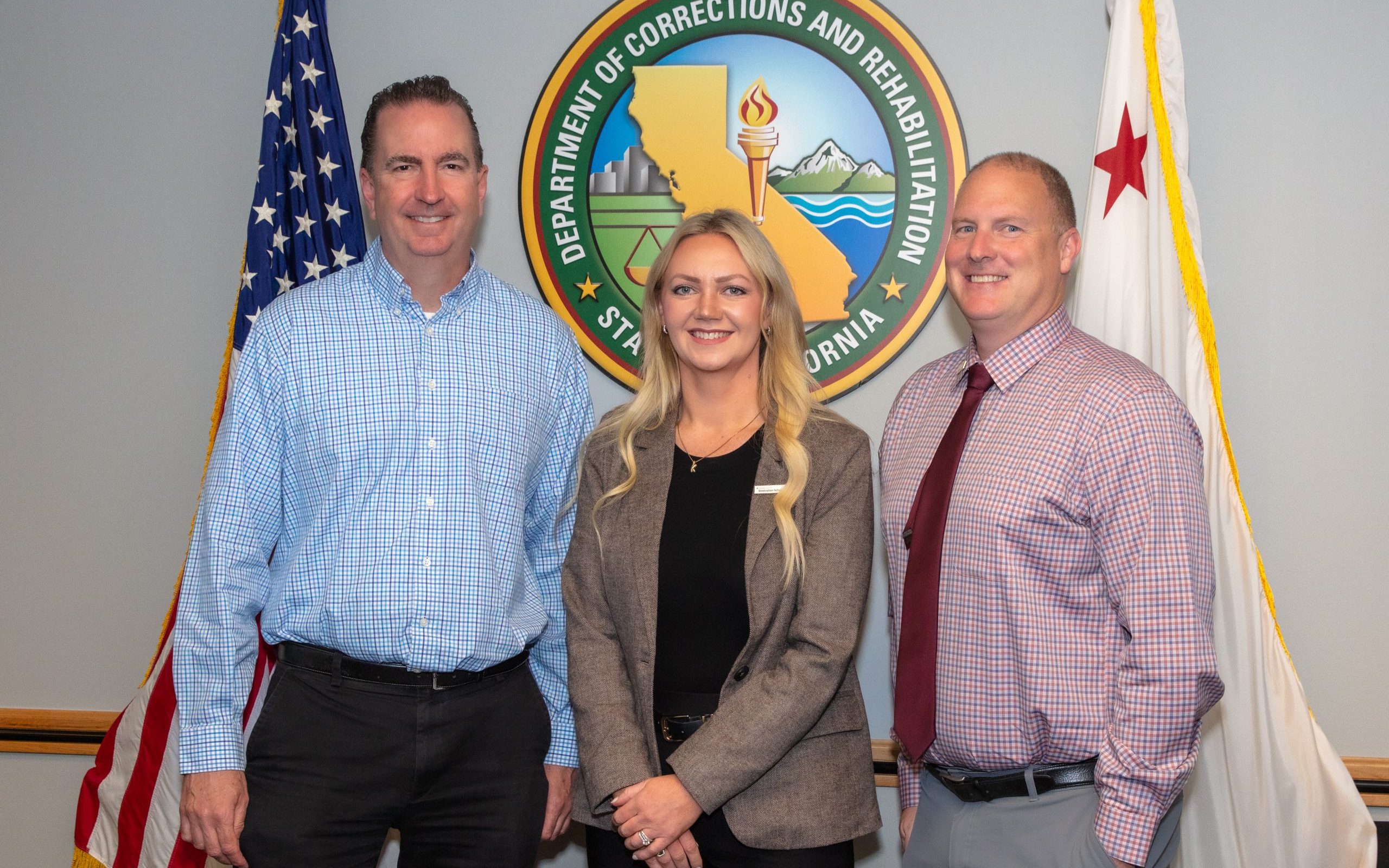 CDCR Secretary Jeff Macomber congratulates Governor's Innovation Fellows graduates Associate Warden Samantha Kissane and Associate Warden Chris Siino.