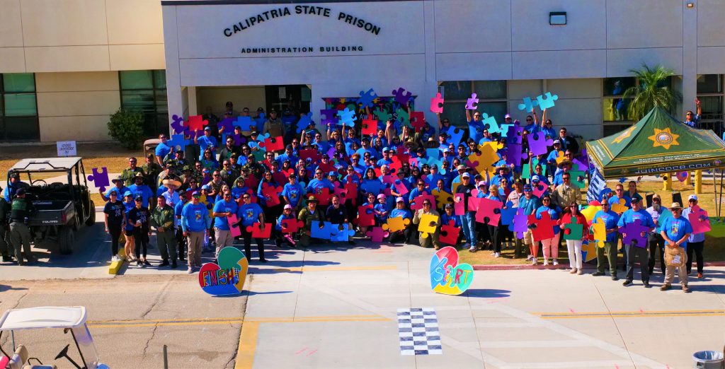 Large group photo of autism walk participants holding colorful puzzle piece posters