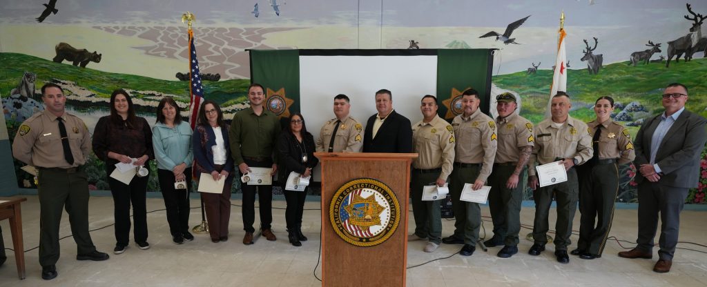 Group photo of leadership and those being honored during a promotion ceremony at CCI-Tehachapi.