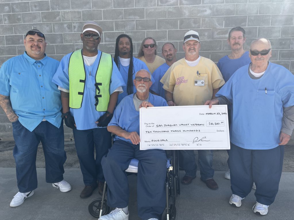 CHCF incarcerated individuals stand with donation check for $10,300 from their food sales