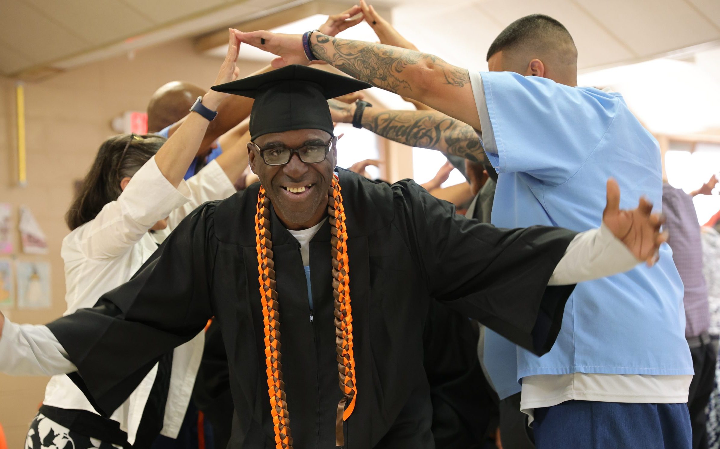 A GRIP graduate at CTF smiles as he walks under an arch of outspread arms.