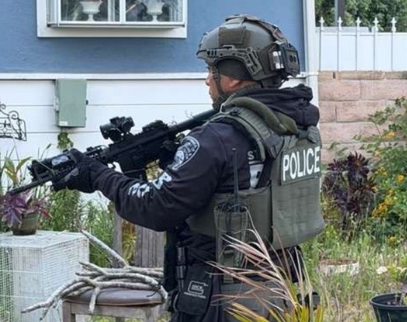 An agent holds a gun during a parole compliance sweep.