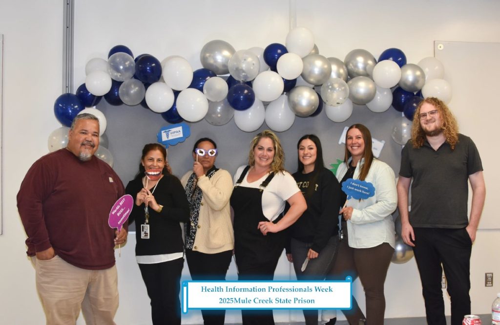 Group of health information staff from MCSP pose in front of backdrop and use photo props