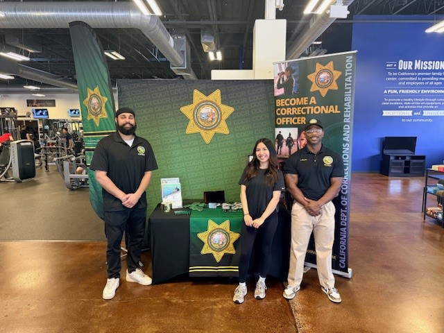 Recruitment staff stand at booth inside fitness facility