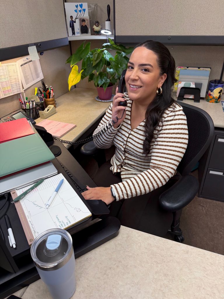 Staff spotlight photo of Isabel Carpio sitting at her desk