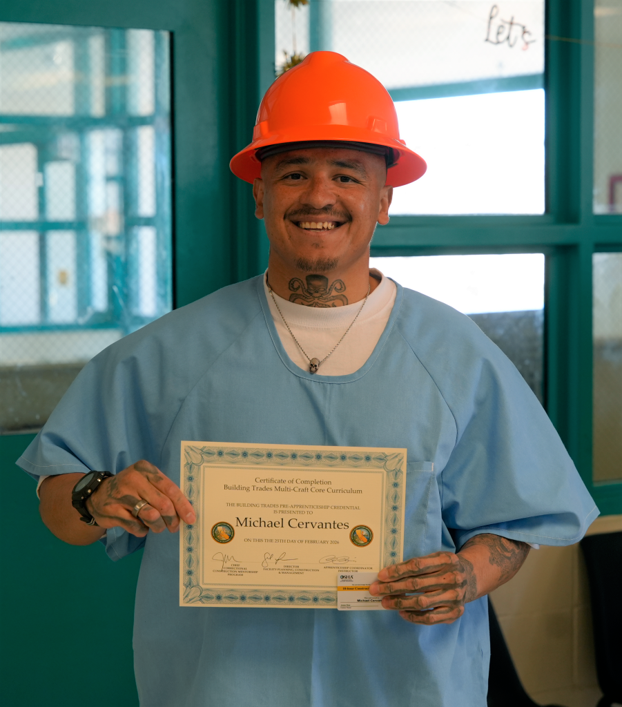 A construction program graduate proudly holds his certificate at an LAC ceremony.