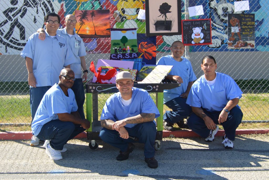 LAC incarcerated individuals pose with artwork