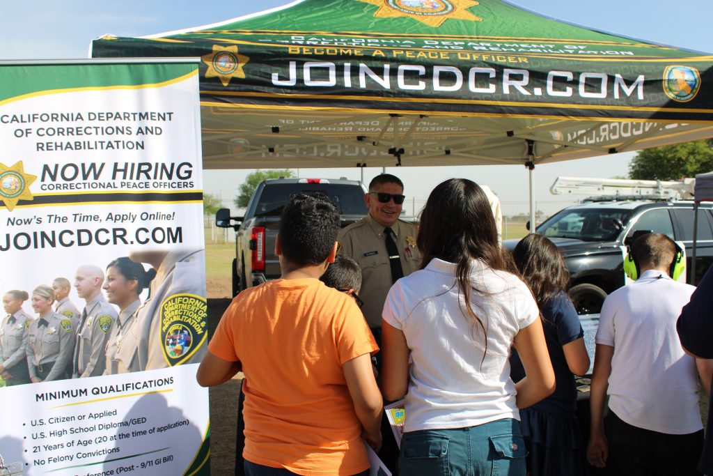 Lieutenant M. Ramos interacts with children at outdoor career day booth