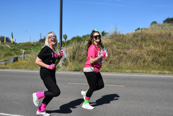 Two MCSP staff jogging in bright 80's themed clothing