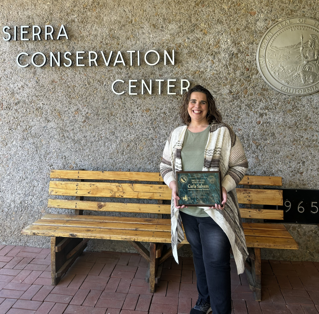 SCC employee of the month stands with plaque
