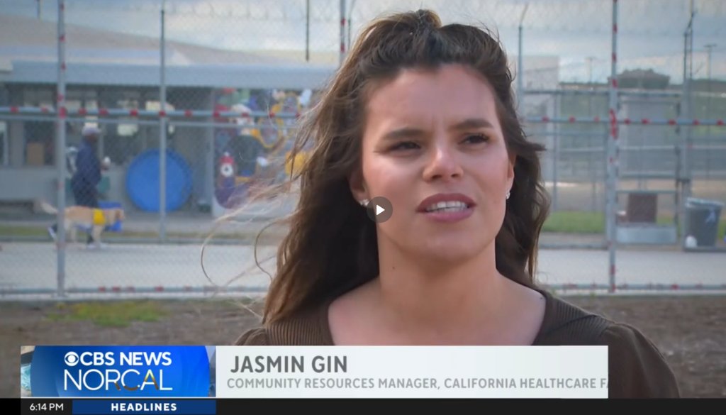 News video screenshot of Jasmine Gin, CHCF Community Resources manager speaking, incarcerate person walking dog in background.