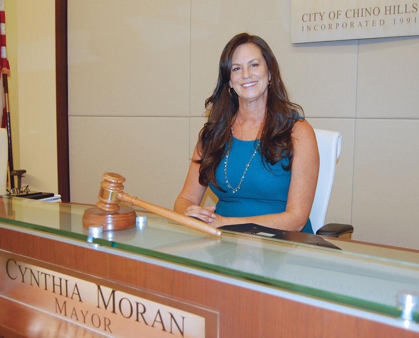 Keynote speaker Chino Hills City Councilwoman Cynthia Moran sits at desk with gavel in front of her