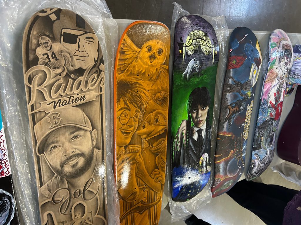 Close up of 5 skatebaords with various artwork such as "raiders nation" and "harry potter" designs