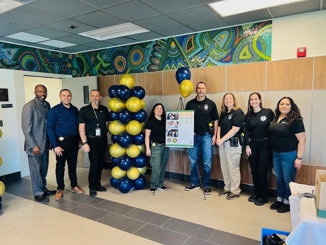 multiple staff members stand around second chance resource fair sign