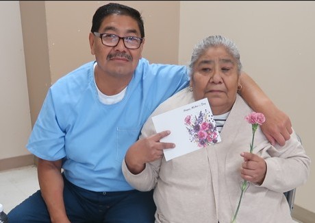 A man hugs a woman at Avenal State Prison during Mother's Day visiting.