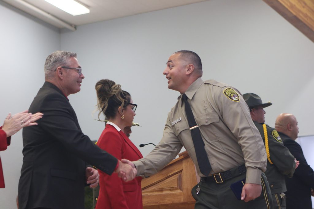 A new officer shakes hands with CDCR executive Bryan Bishop.