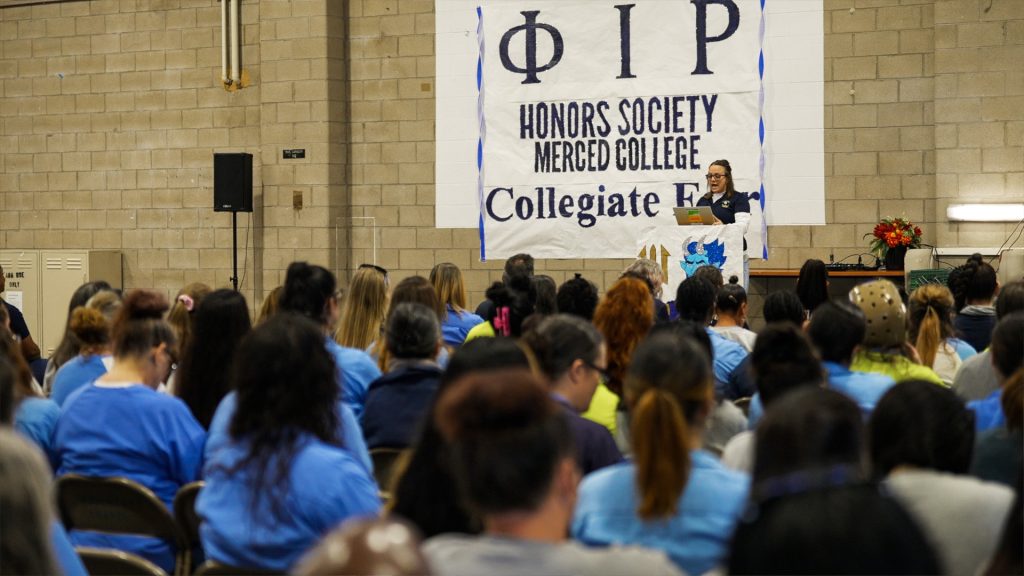 A woman speaks at a lectern at CCWF during a collegiate fair.