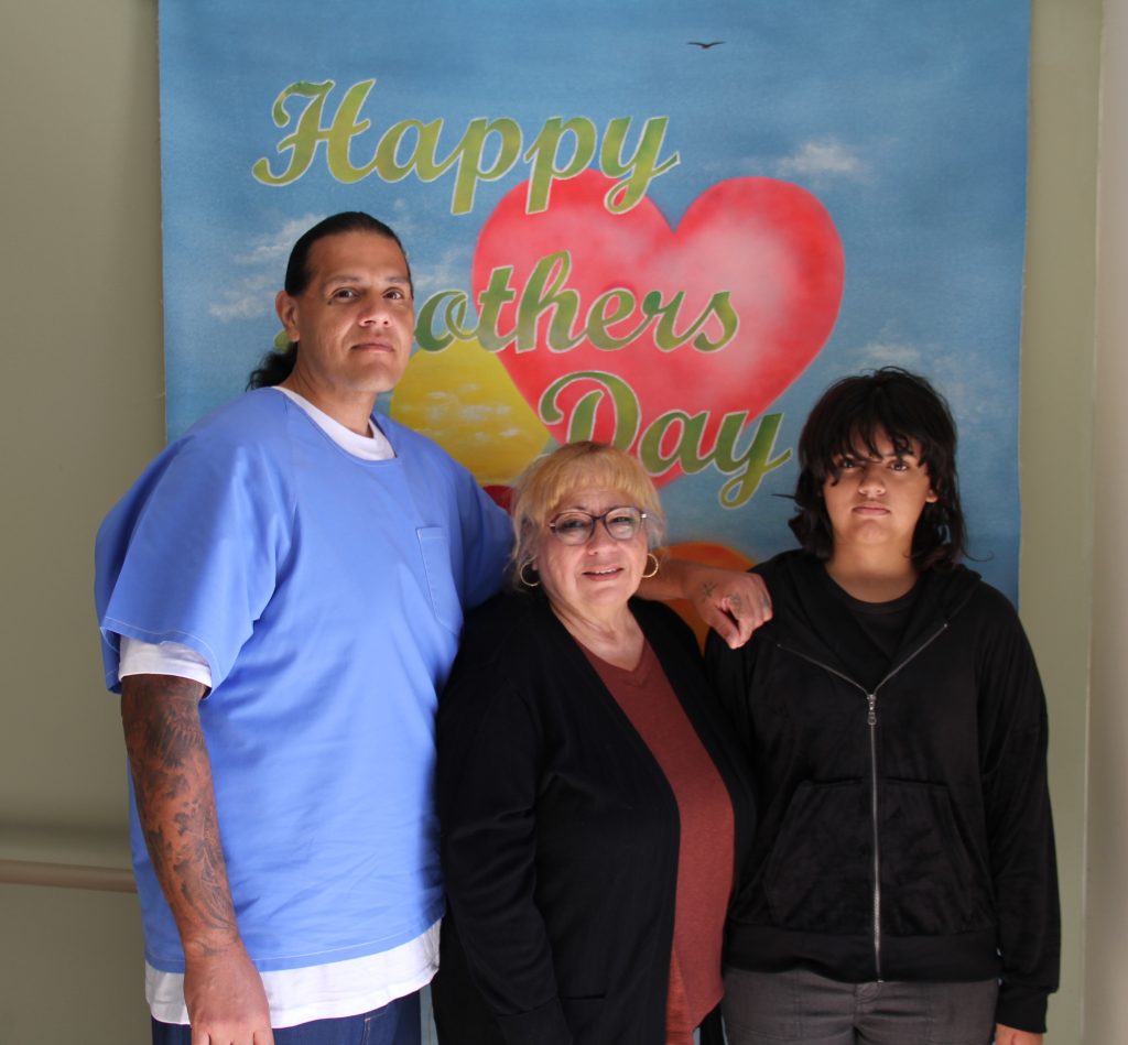 An incarcerated person and two women at CHCF during a special visiting event.