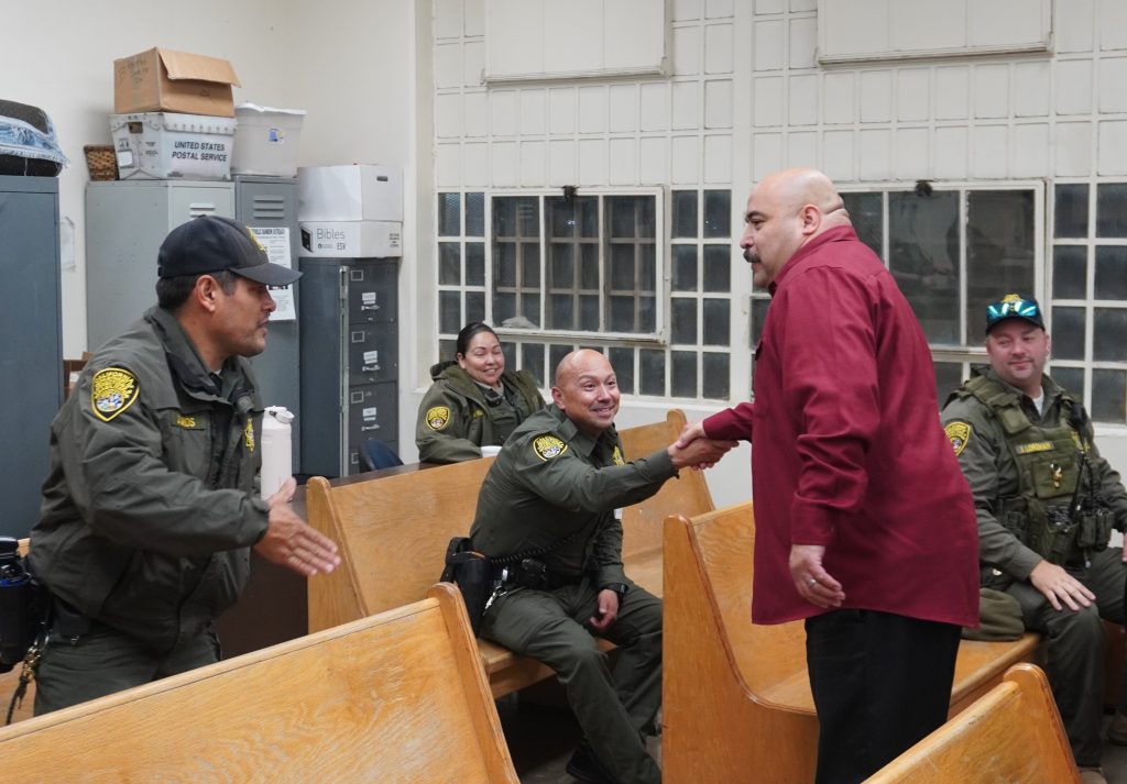 In the chapel, warden shakes hands with CIM staff working at night.