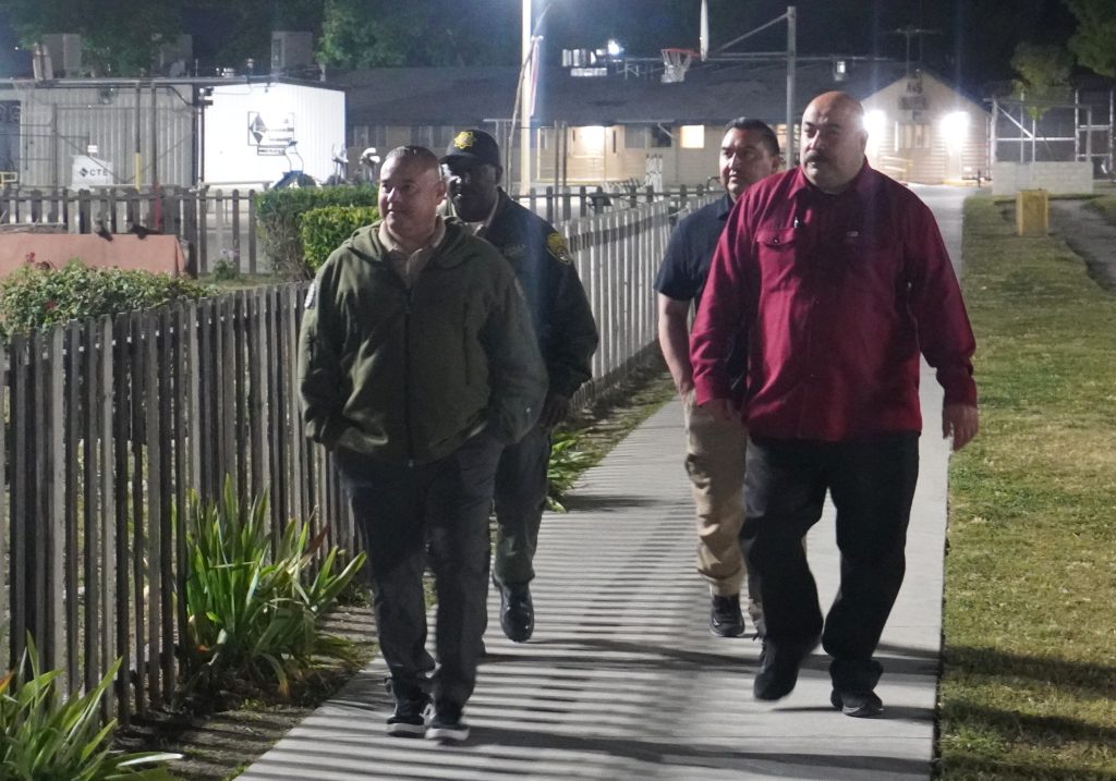CIM warden walks with staff at night.