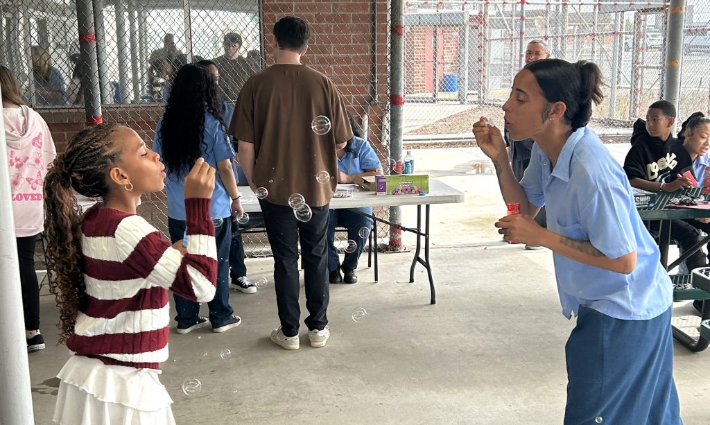 An incarcerated mother blows bubbles with her daughter at CIW in Corona during Mother's Day visiting.