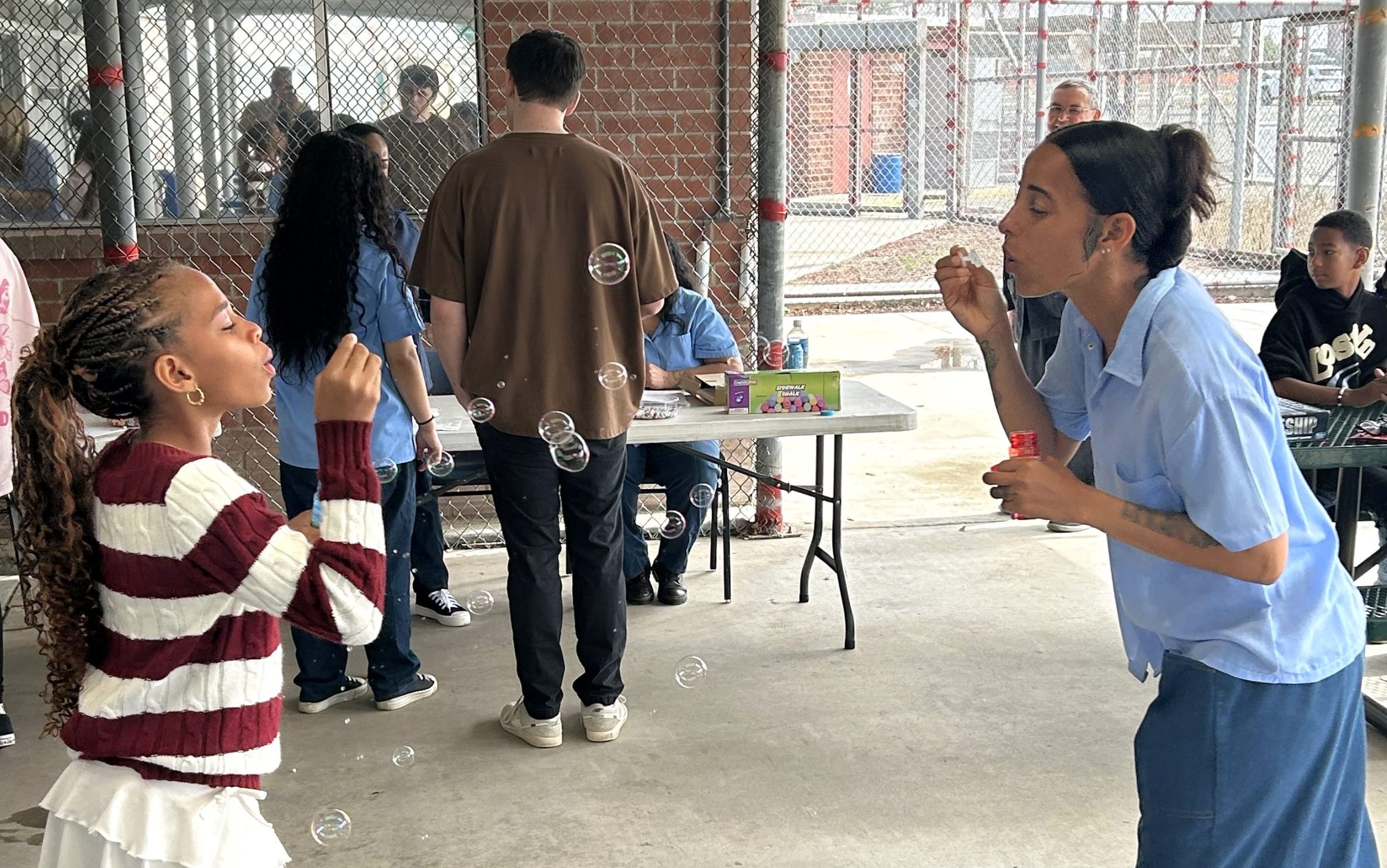 An incarcerated mother blows bubbles with her daughter at CIW in Corona during Mother's Day visiting.