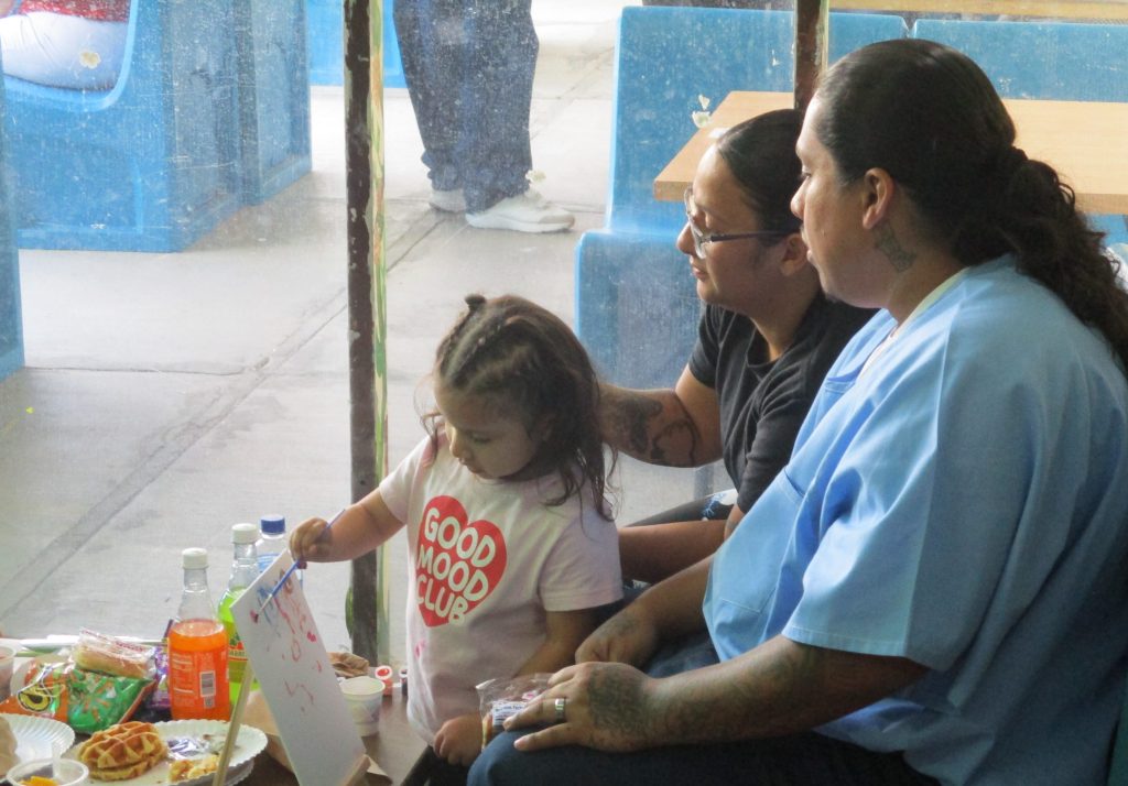 Woman does crafts with her young child at CMF for Mother's Day visiting.