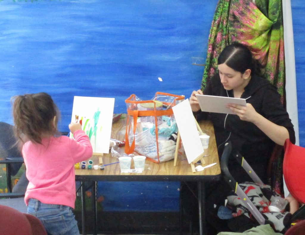 A woman does crafts with her young child at CMF for Mother's Day visiting.