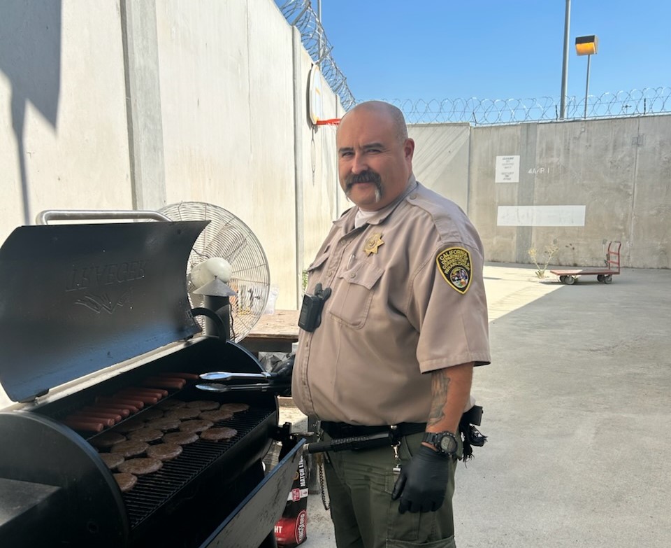 A correctional officer grills hamburgers and hotdogs at CSP-Corcoran.