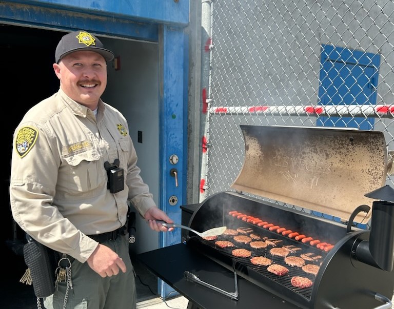 During a staff appreciation event at CSP-Corcoran, an officer grills hotdogs and hamburgers.