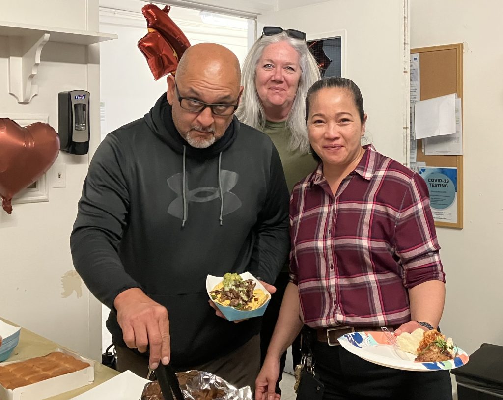 Three staff members get food at a CRC-Norco celebration.